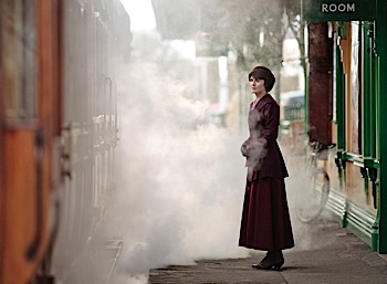 woman outside train station near steam engine